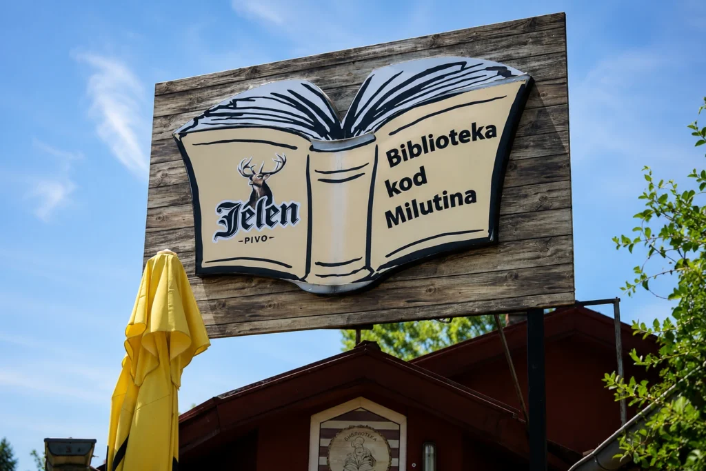 Biblioteka kod Milutina - 5 detalja koje će razumeti samo pravi ljubitelji knjiga Velika drvena reklamna tabla Biblioteka kod Milutina sa motivom otvorene knjige.